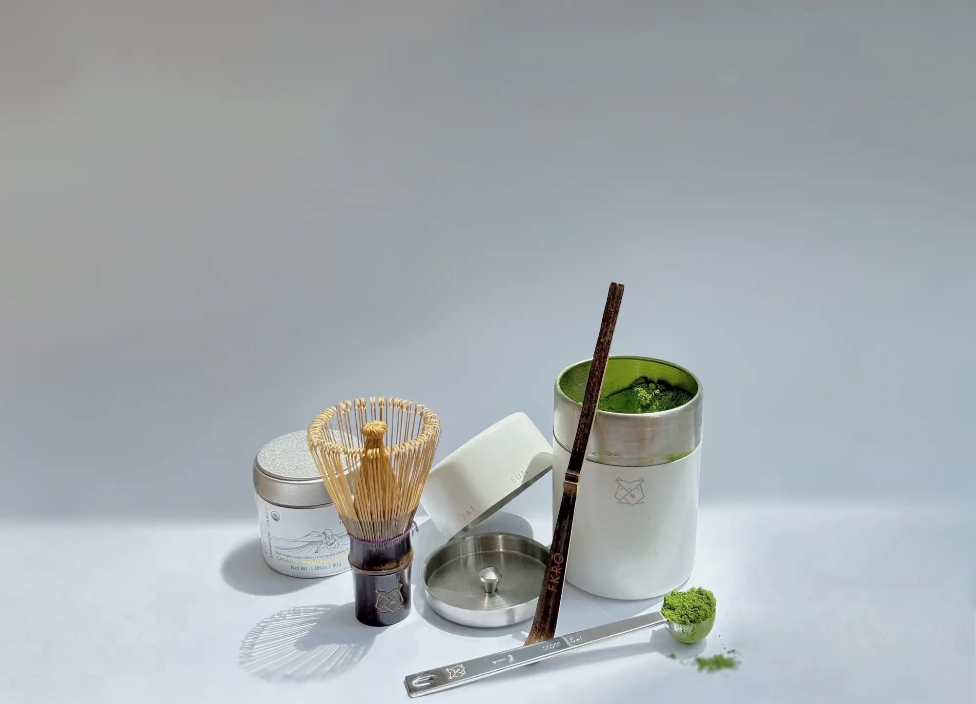 White ceramic matcha tea set with silver lid and bamboo whisk